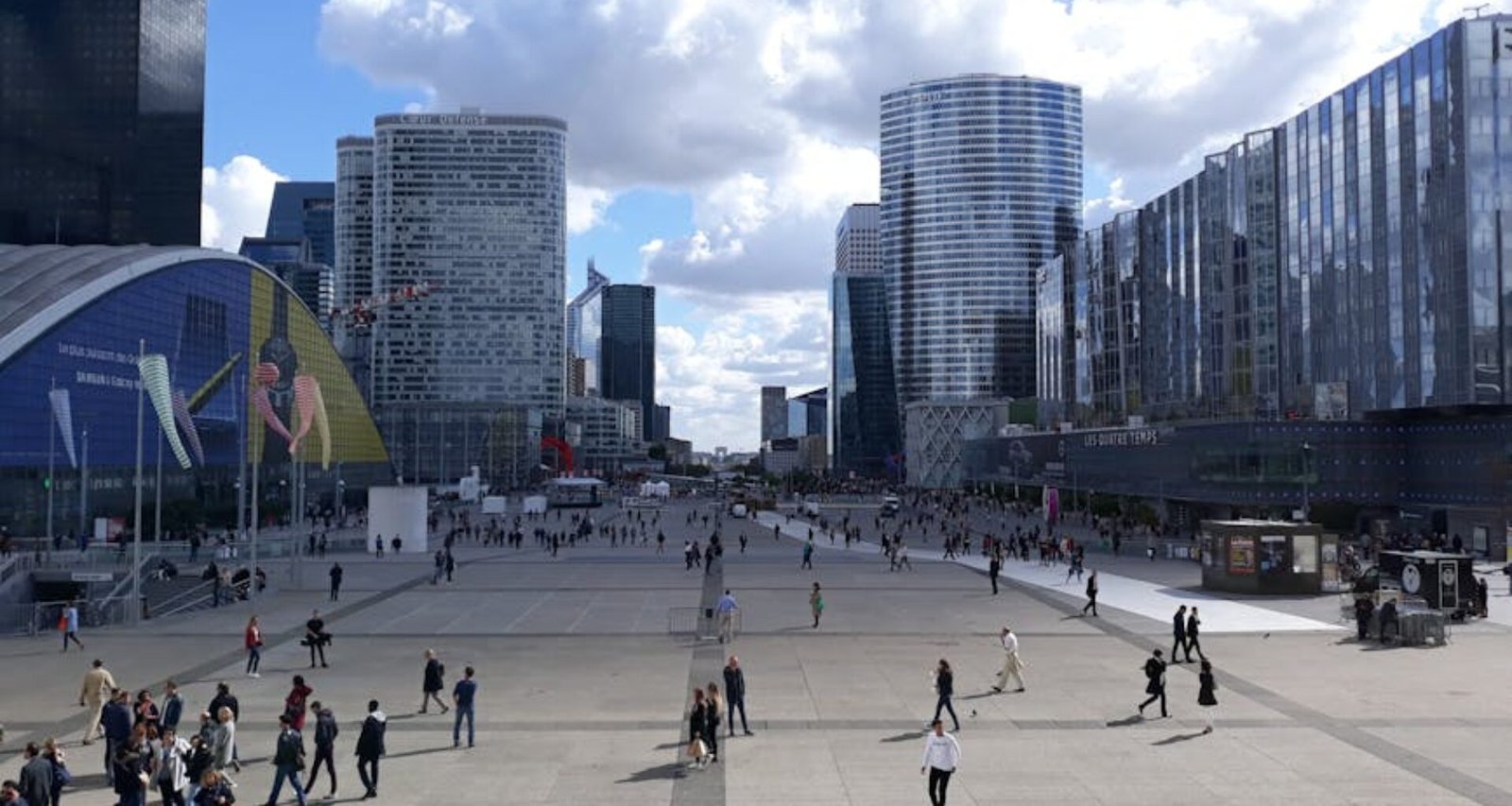 A vibrant scene of La Défense in Paris with modern architecture and a lively crowd.